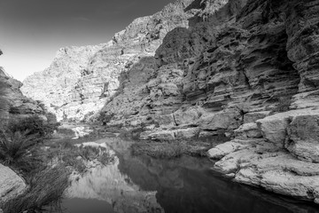 Black and white of Wadi Shab river canyon with rocky cliffs and green water springs - Sultanate of Oman