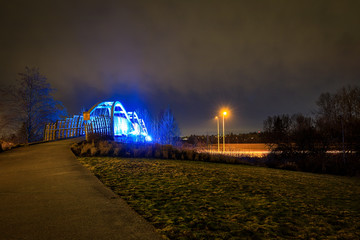 Fototapeta na wymiar Pedestrian overpass lit up in bright blue LEDs at night
