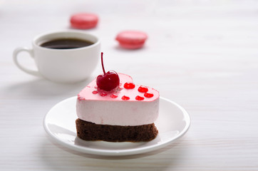 souffle cake in the form of heart  with cup of coffe and macaroons on a wooden table
