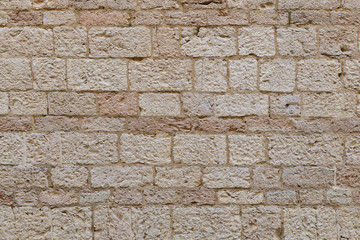 A fragment of an old city wall made of stones carved from yellow-orange sandstone. Close-up. Background. Pattern.