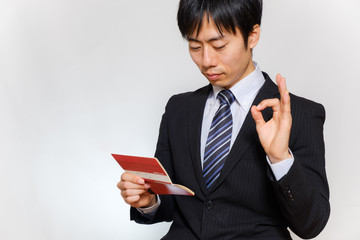 通帳を持ってOKサインをする男性
