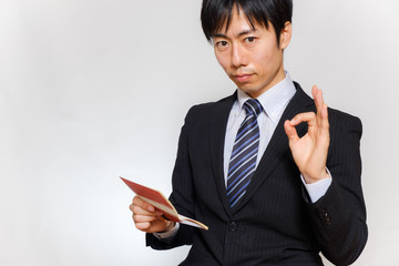 通帳を持ってOKサインをする男性