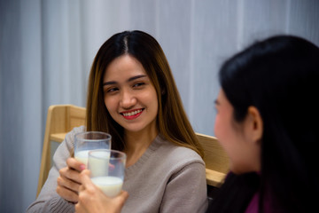 Young Asian beautiful woman enjoy drink a glass of milk on bed with happy mood in bedroom at night time