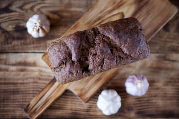 A loaf of black rye homemade bread lies on a wooden Board