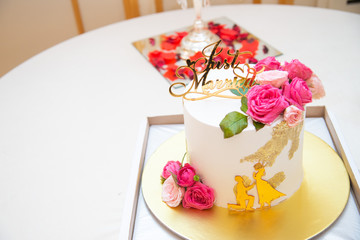 Wedding cake with just married topper. Luxurious wedding cake with flowers.