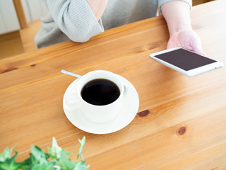 コーヒーを飲みながらスマートフォンを見る女性