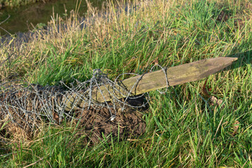 Wooden pole full of barbed wire left in the nature, very dangerous for humans and animals