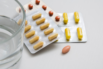 Pills and glass of water on white background.