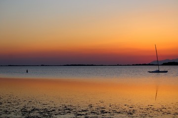 Fototapeta premium sailboat moored on the sea at sunset and headland on the background
