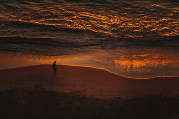 Person walking on beach during sunset