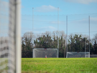 Training ground for Irish national sports rugby, hurling and comogie. Clear blue sky, green grass of the pitch. Four goal posts with nets.