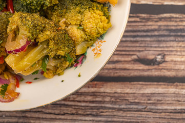 Vegetable salad in a white ceramic plate on a wooden background. Close up.
