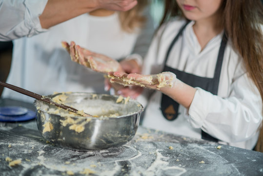 happy family in kitchen. Homemade food and little helper. Cropped image of mother and daughter are cooking on kitchen. Having fun together while making cakes and cookies. hands closeup.