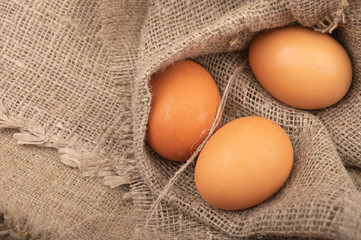 Chicken eggs on a background of rough homespun fabric. Rustic treat. Close up.