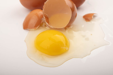 Broken chicken egg and eggs scattered on a white background. Close up.