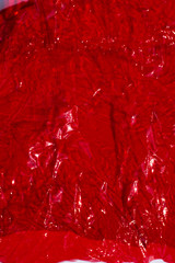Thin sheet of red colour cellophane with shiny crumpled surface texture, Abstract background, Light & Shadow concept