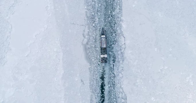 Boat Float Through the Surface of a Frozen Lake Baikal.Travel Concept Winter Background. View From Above Drone Follow a Ship Icebreaker Moving on Ice.