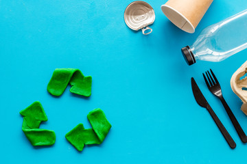 Green recycle icon near plastic, paper, glass waste on blue background top-down copy space