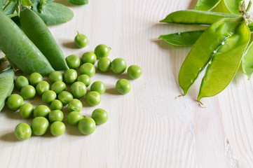 Young green peas on white wooden background.