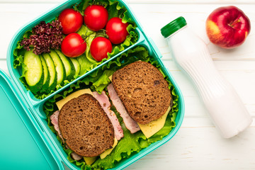 Top view of school lunch box with sandwiches and vegetables and a bottle of yogurt: a concept of healthy and balanced nutrition