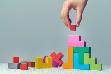 Hand arranging wood cube stacking as step stair. Business concept growth success process on blue...