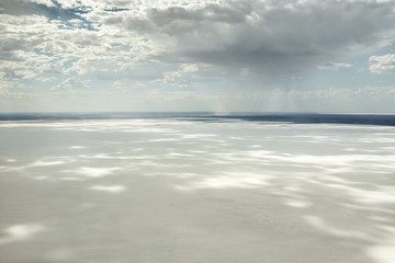 Fototapeta na wymiar Kati Thanda-Lake Eyre Salt Flats outback South Australia aerial photography with rainfall backdrop and dramatic clouds casting shadows on the white salt lake, Australia
