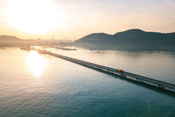 Aerial view from drone, truck freight containers to the downtown on the pier in beautiful light sundown, professional business logistics and transportation of cargo ship.