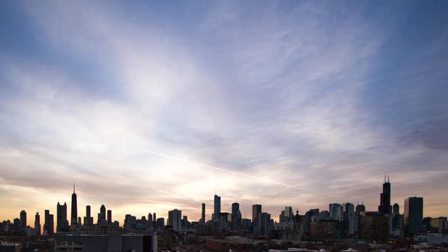 Beautiful pink and purple sunrise to start the day behind the Chicago skyline with fast moving clouds time lapse