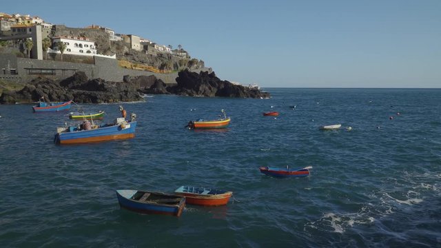 Fishing boats floating with Camara de lobos village in the background, Madeira island, Portugal.