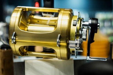large size fishing multiplier reel on the counter in a fishing store. Shallow depth of field