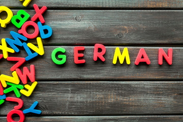 Learn German. Concept with letters on wooden background top-down copy space