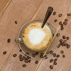 Top view of cup of hot latte or cappuccino in a glass cup on wooden table. Coffee with milk foam with copy space