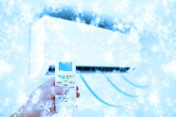 Aircondition cold blowing air concept with a person's hand holding a remote.