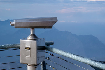 Close up of observation binoscope or binoculars on top of tahtali mountain with mountains and cloudy sky background. Touristic binoculars, telescope.