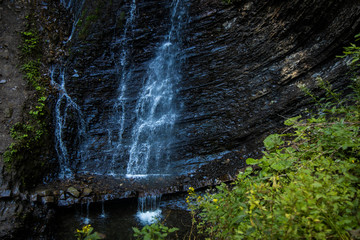 Fototapeta premium forest waterfall water fuzzy motion rock cascade scenic view outdoor environment and green foliage foreground