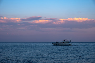 Luxury yacht on mediterranean sea at evening time with beautiful gold cloudy sky background.