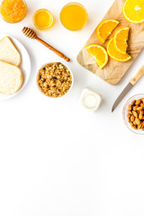 Morning granola near toast and oranges on white background top-down frame copy space
