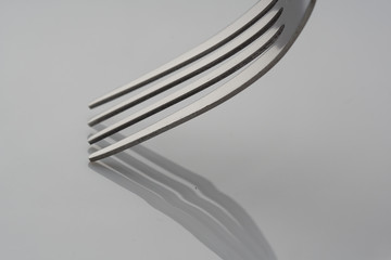 close up on shiny  fork with grey shadow over white plate