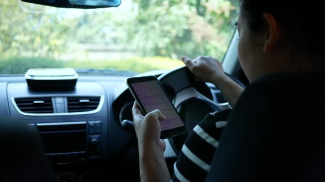Asian young woman using the Google Maps application on a smartphone to search for directions while driving. Concept of using technology in transportation.