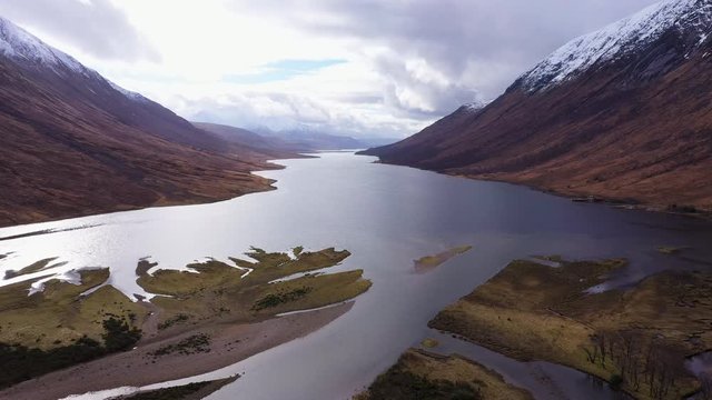 aerial drone footage of winter in glen etive in the argyll region of the highlands of scotland showing clear bright white snow on the mountains of glencoe and the surrounding region