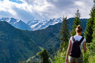 Traveling girl with backpack hiking in the mountains, freedom concept. Hiking in Almaty mountains.
