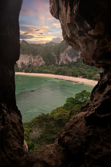 Railey beach view from cave on top of high cliff and longtail boat on tranquil sea in sunset sky