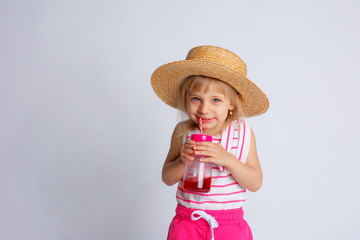 a little girl in summer clothes and a bottle of juice with a straw on a white background. The concept of summer vacation