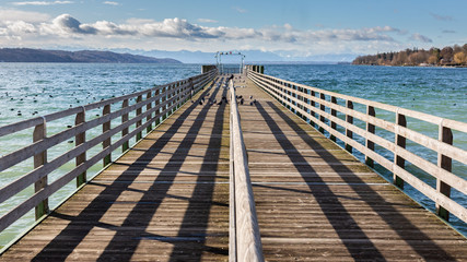 Starnberg, Bavaria / Germany - Feb 26, 2020: Straight view on a wooden pier at Lake Starnberg...