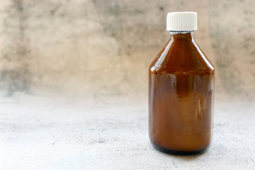 Brown bottle of medicine on a stone table background
