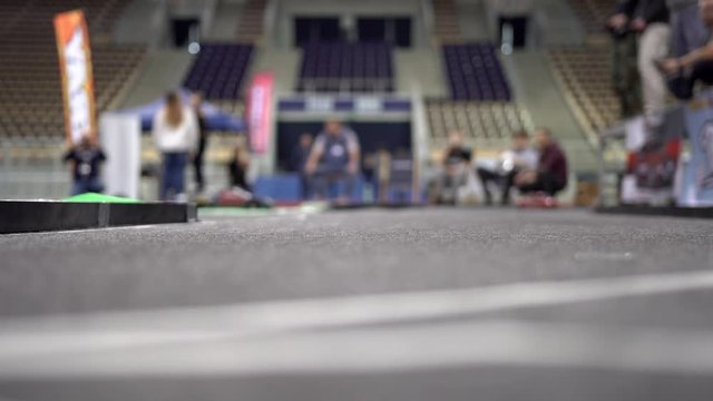 Small red RC car on the track drifting into a left turn. Racing battery charged cars controlled with a remote controller. RC cars on an asphalt polygon drifting. RC drift cars on track. 