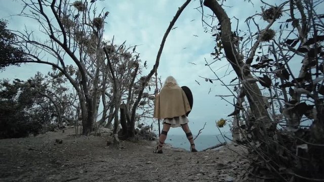 The authentic dressed man looks out over the sea on a desert island with birds.