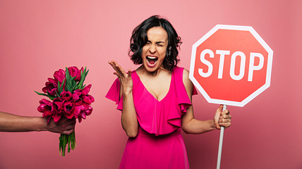 Women rights. Flowers enough. Beautiful stylish serious young woman in a pink dress shows a big red...
