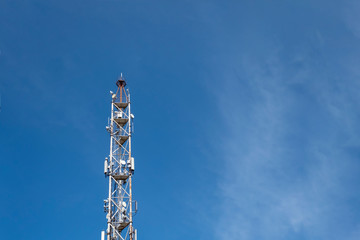 Telecommunication tower with lot of antennas on blue sky background.
