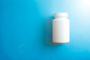 Closeup of white pill bottle on blue background.Health care, medical concept.